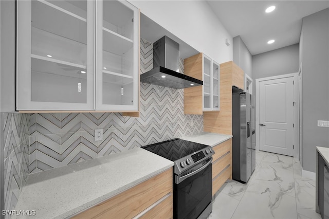 kitchen with glass insert cabinets, wall chimney range hood, appliances with stainless steel finishes, recessed lighting, and marble finish floor