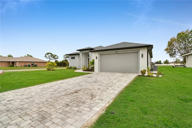 prairie-style house with stucco siding, decorative driveway, an attached garage, a front lawn, and central AC