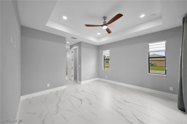empty room with a raised ceiling, baseboards, a ceiling fan, and recessed lighting
