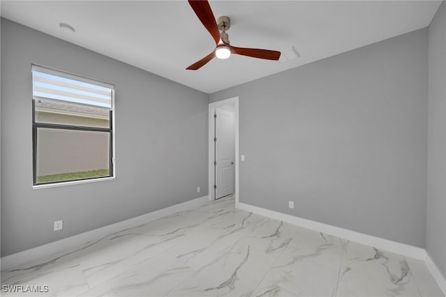 unfurnished room with marble finish floor, baseboards, and a ceiling fan