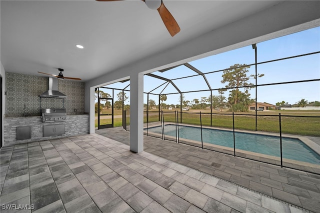 pool with exterior kitchen, grilling area, a ceiling fan, a patio area, and glass enclosure