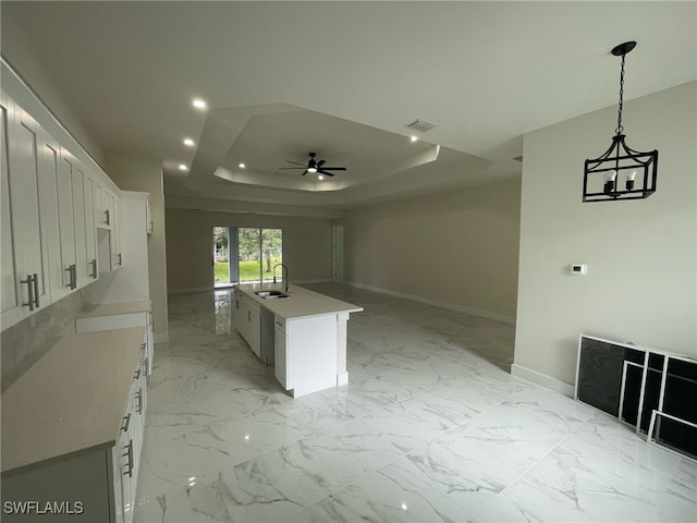 kitchen with a sink, a tray ceiling, recessed lighting, and marble finish floor