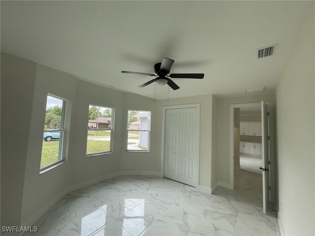 unfurnished bedroom featuring a closet, baseboards, a ceiling fan, visible vents, and marble finish floor