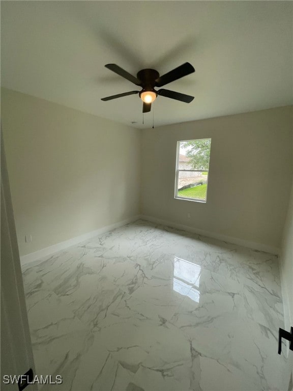 spare room featuring marble finish floor, baseboards, and a ceiling fan