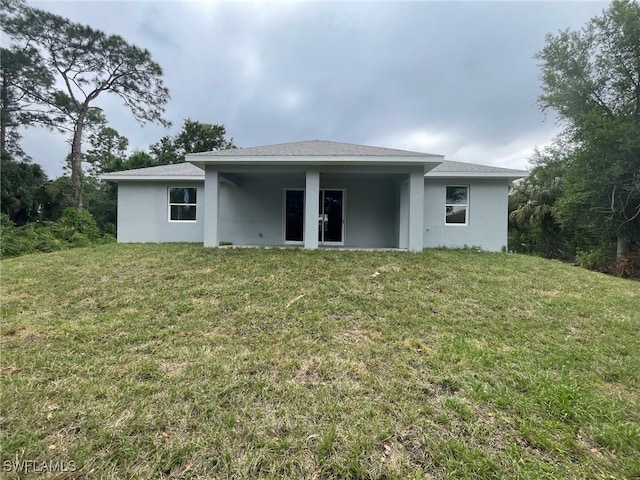 back of house with a yard and stucco siding
