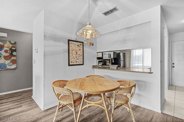 11170 Caravel Cir Unit 210, Fort Myers, FL 33908 - dining space with vaulted ceiling, wood finished floors, visible vents, baseboards, and a notable chandelier