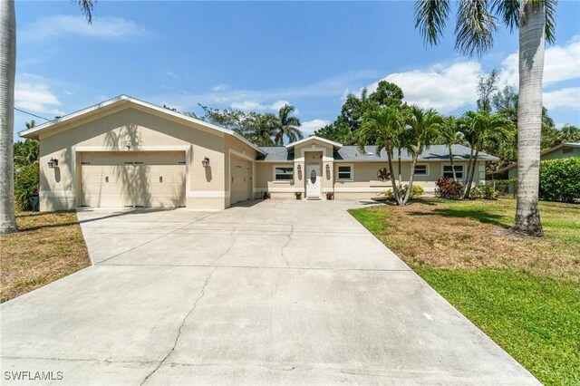 single story home with a garage, driveway, a front lawn, and stucco siding