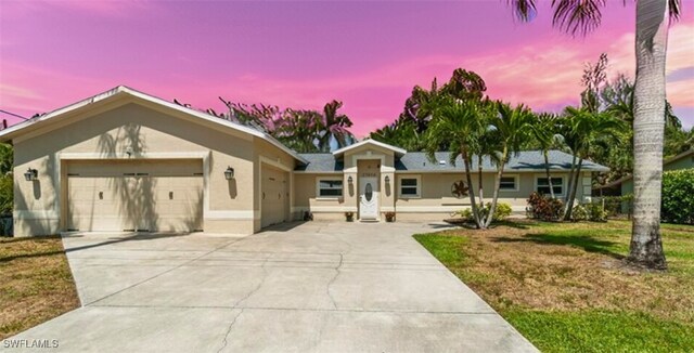 ranch-style house with a garage, stucco siding, driveway, and a front lawn