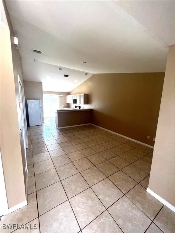 interior space with visible vents, open floor plan, a peninsula, light tile patterned flooring, and lofted ceiling