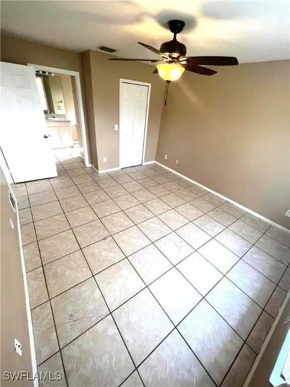 empty room with visible vents, ceiling fan, baseboards, and light tile patterned floors