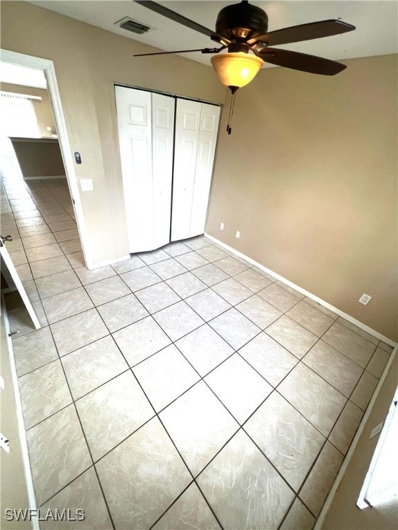 unfurnished bedroom featuring light tile patterned floors, visible vents, a closet, and a ceiling fan
