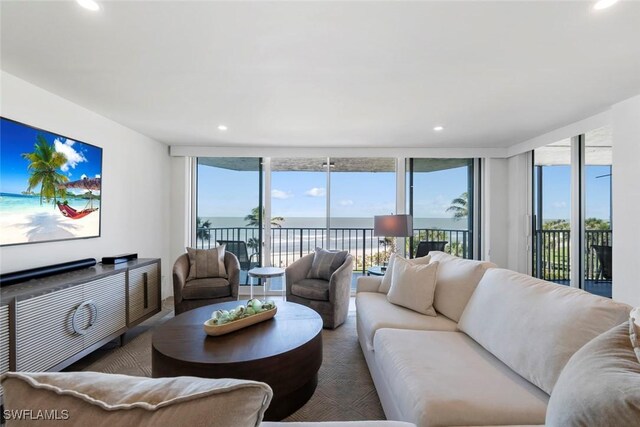 living room with a water view, recessed lighting, and a wall of windows
