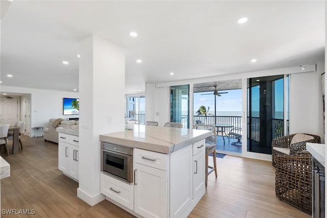 kitchen featuring light wood-style flooring, a breakfast bar area, white cabinets, and recessed lighting