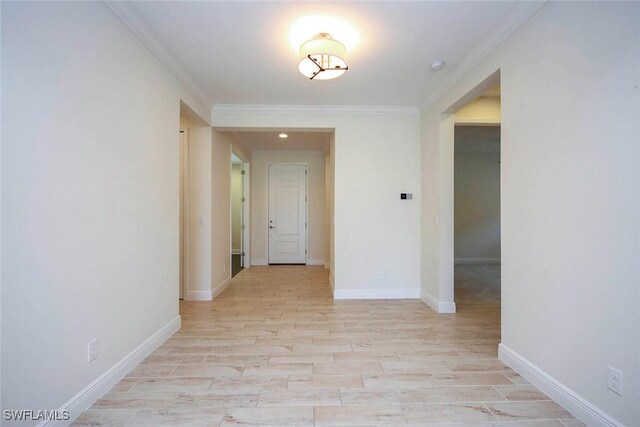 hallway featuring ornamental molding, light wood-style floors, and baseboards