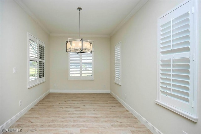unfurnished room featuring a chandelier, light wood-style flooring, ornamental molding, and baseboards