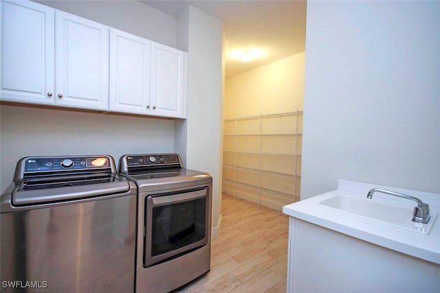 washroom with independent washer and dryer, cabinet space, and light wood-style flooring