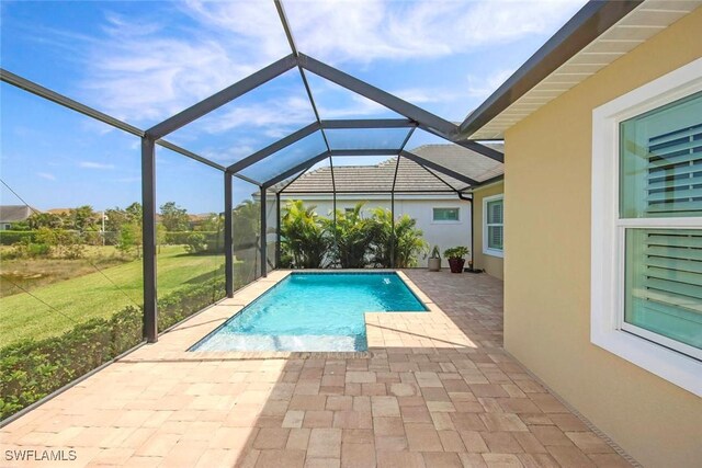 outdoor pool featuring a patio, a lawn, and glass enclosure