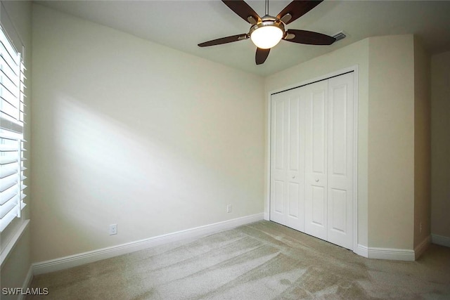 unfurnished bedroom featuring carpet, baseboards, a closet, and a ceiling fan