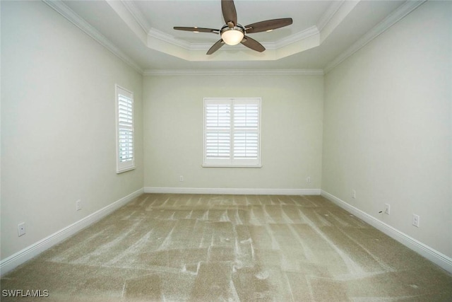 empty room featuring plenty of natural light, a ceiling fan, carpet flooring, a tray ceiling, and crown molding