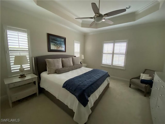 bedroom featuring a raised ceiling, carpet floors, ornamental molding, and a ceiling fan