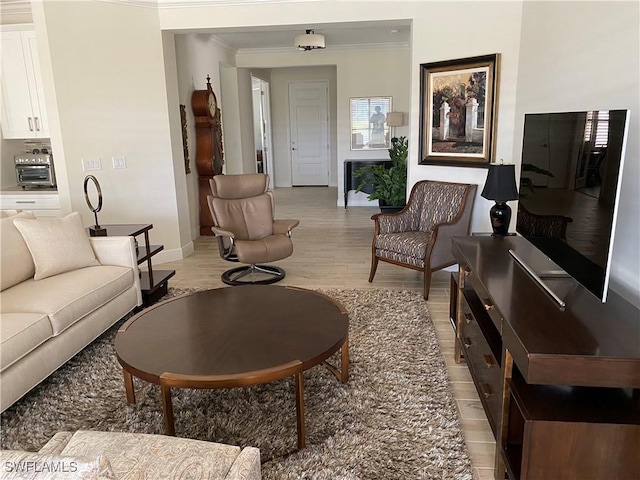 living room featuring baseboards, light wood-style floors, and ornamental molding