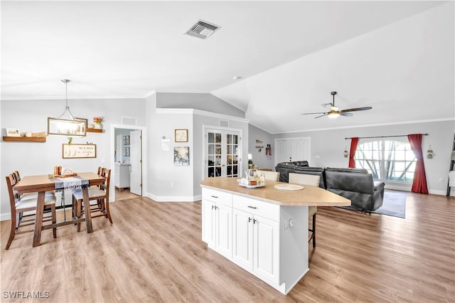 11741 Red Hibiscus Dr, Bonita Springs, FL 34135 - kitchen with baseboards, vaulted ceiling, light countertops, white cabinetry, and visible vents
