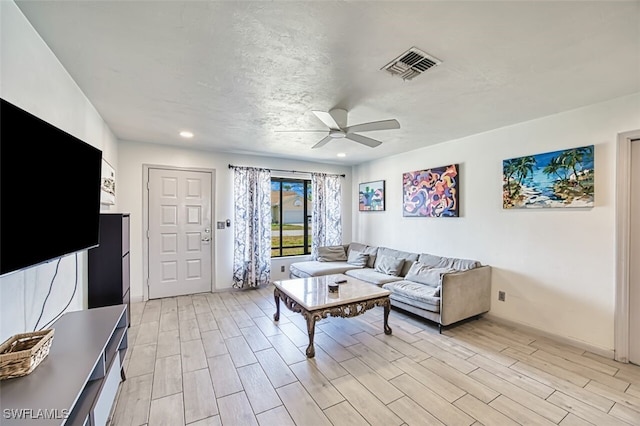 living room featuring light wood-style floors, a ceiling fan, visible vents, and recessed lighting