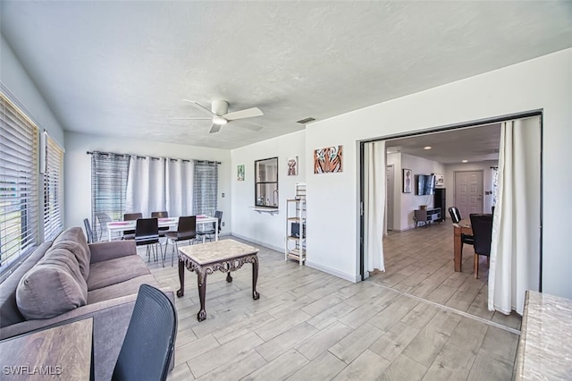 living area with visible vents, baseboards, a ceiling fan, and wood tiled floor