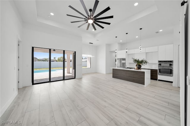 2138 SW 3rd Ave, Cape Coral, FL 33991 - unfurnished living room featuring a raised ceiling, a towering ceiling, recessed lighting, ceiling fan, and light wood-type flooring