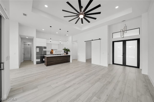 2138 SW 3rd Ave, Cape Coral, FL 33991 - living room featuring a tray ceiling, a barn door, recessed lighting, a towering ceiling, and light wood finished floors