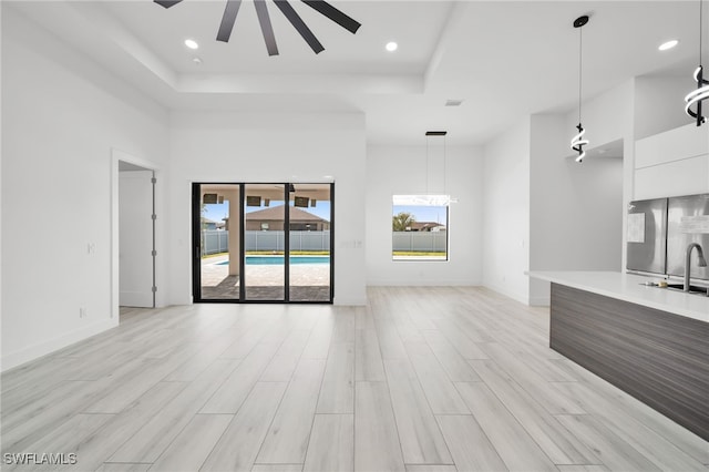 2138 SW 3rd Ave, Cape Coral, FL 33991 - unfurnished living room featuring a tray ceiling, ceiling fan, light wood-style floors, recessed lighting, and a towering ceiling