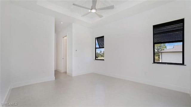 2343 Oil Well Rd, Naples, FL 34120 - empty room featuring a tray ceiling, concrete flooring, a ceiling fan, and plenty of natural light