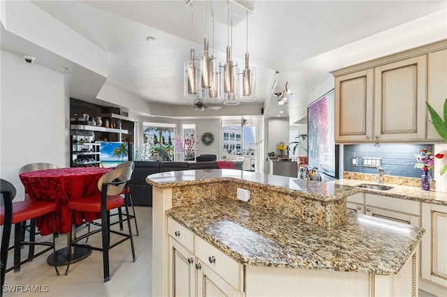 14270 Royal Harbour Ct Unit 323, Fort Myers, FL 33908 - kitchen featuring cream cabinetry, a chandelier, open floor plan, light stone countertops, and backsplash