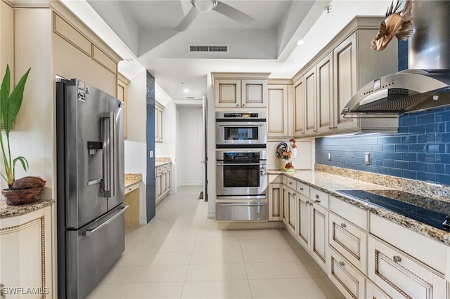 14270 Royal Harbour Ct Unit 323, Fort Myers, FL 33908 - kitchen featuring appliances with stainless steel finishes, a warming drawer, wall chimney exhaust hood, cream cabinets, and light tile patterned floors