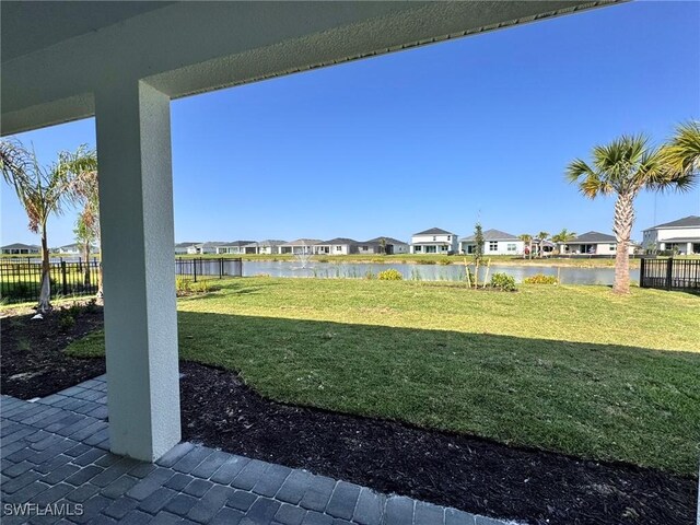 view of yard with a water view, fence, and a residential view