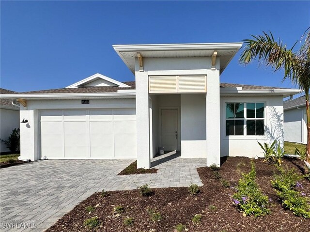 view of front facade featuring decorative driveway, an attached garage, and stucco siding