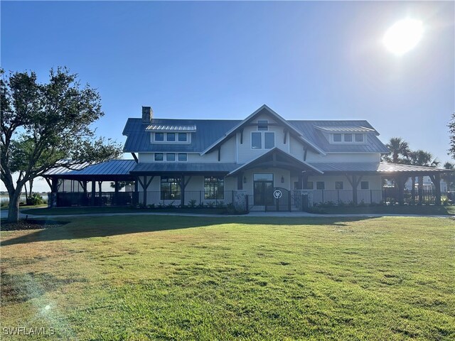 view of front facade featuring a chimney, a front lawn, and metal roof