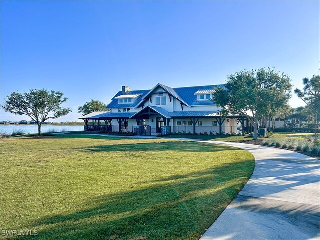 view of front of house with a water view, a chimney, metal roof, and a front yard
