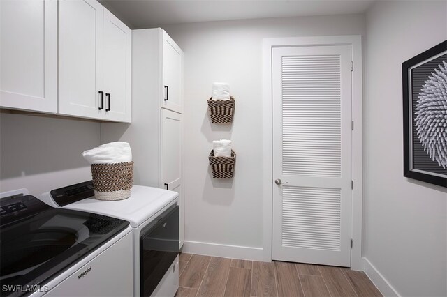 laundry room with baseboards, cabinet space, wood finished floors, and washer and dryer
