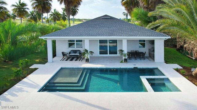 rear view of property with a pool with connected hot tub, a shingled roof, a patio area, and stucco siding