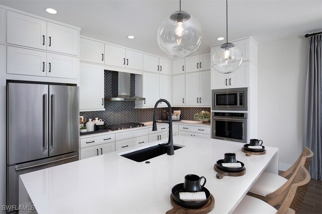 kitchen with wall chimney range hood, appliances with stainless steel finishes, a kitchen breakfast bar, recessed lighting, and decorative backsplash