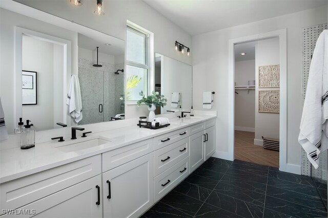 full bathroom featuring double vanity, a sink, baseboards, and a shower stall