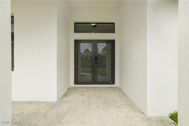 entrance to property featuring french doors and stucco siding