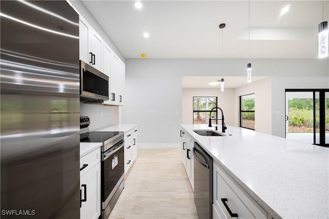 kitchen with light stone counters, a sink, stainless steel appliances, decorative light fixtures, and recessed lighting