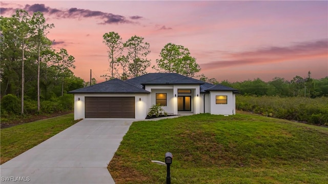 prairie-style house with stucco siding, a lawn, concrete driveway, and a garage