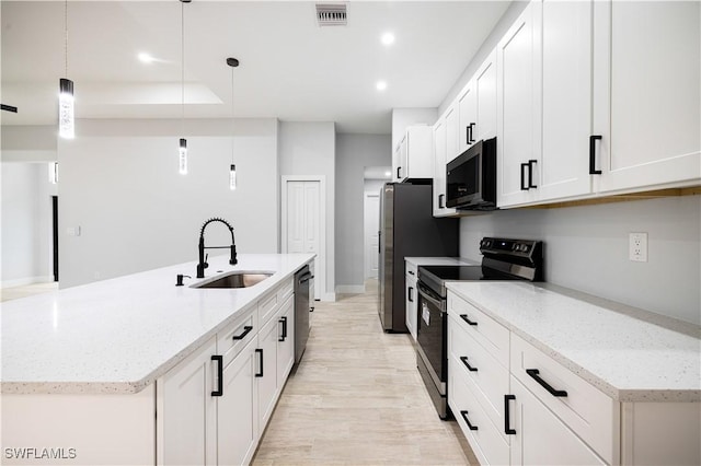 kitchen with a sink, light wood-style floors, a center island with sink, appliances with stainless steel finishes, and visible vents