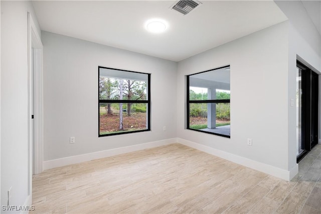unfurnished room featuring baseboards, visible vents, and light wood-style floors