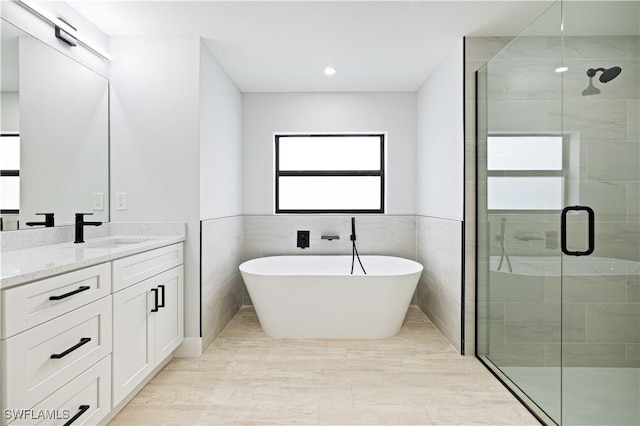 full bathroom featuring a freestanding bath, a shower stall, tile walls, and vanity
