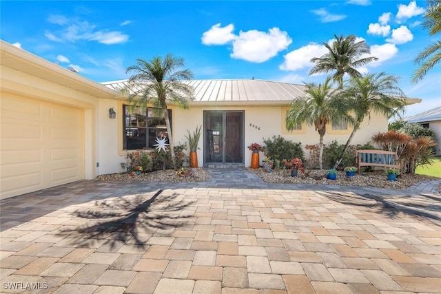 2556 SW 28th Pl, Cape Coral, FL 33914 - view of front of property featuring a garage, stucco siding, decorative driveway, a standing seam roof, and metal roof
