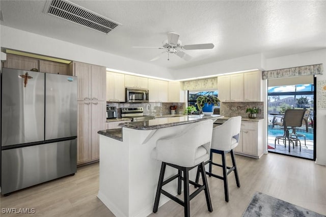2556 SW 28th Pl, Cape Coral, FL 33914 - kitchen featuring appliances with stainless steel finishes, light wood-style floors, a center island, decorative backsplash, and visible vents